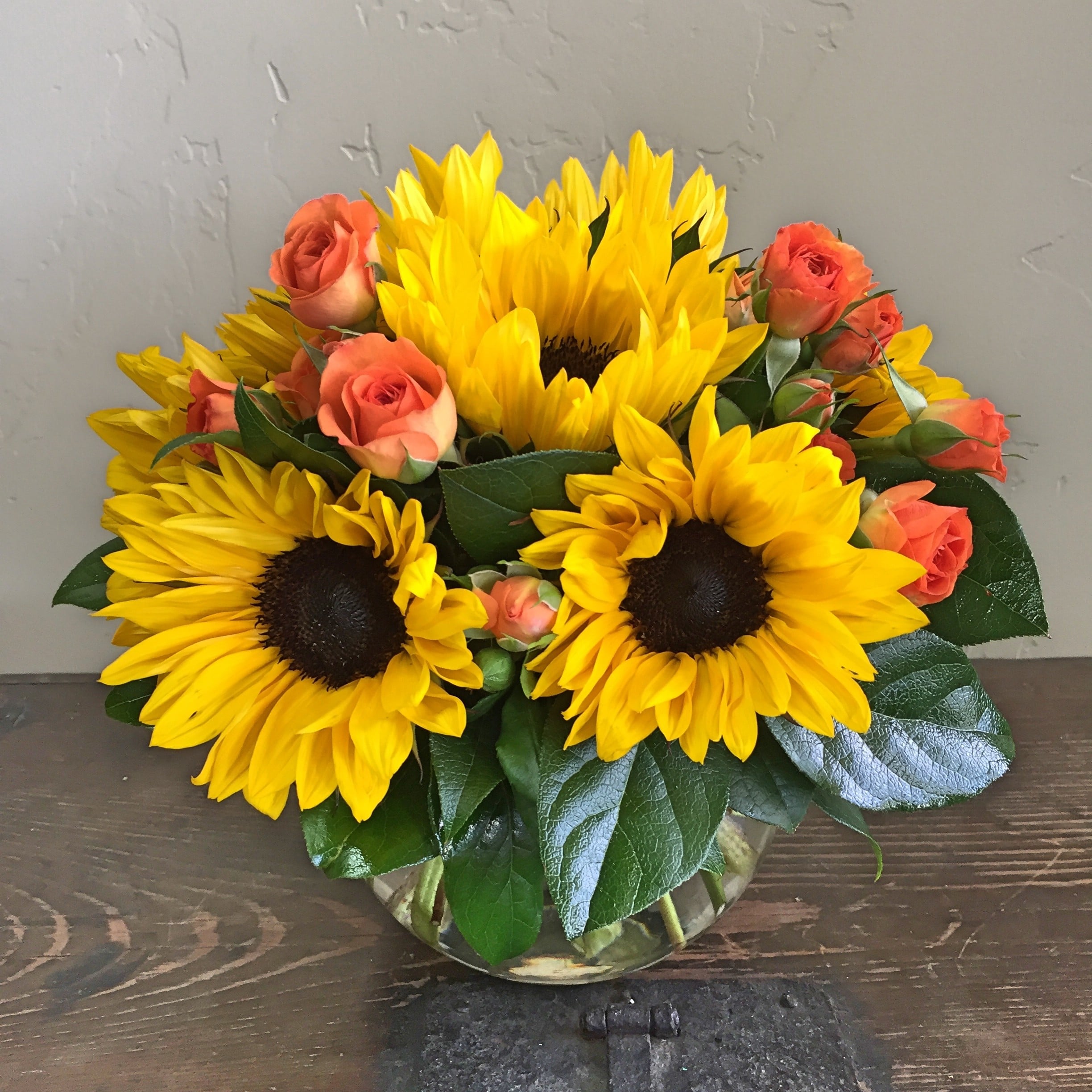 sunflowers, roses and greens in a small vase