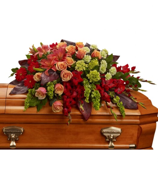 An overflowing of love and respect is joyfully expressed in this truly magnificent casket spray of orange roses and lilies and other brilliant blooms.